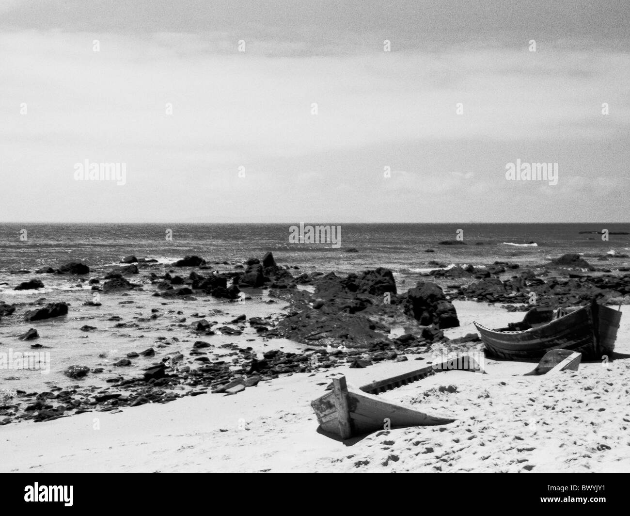 Boote Felsen Klippen Küste Meer Sand schwarzen und weißen Steinen Strand Meer Stockfoto