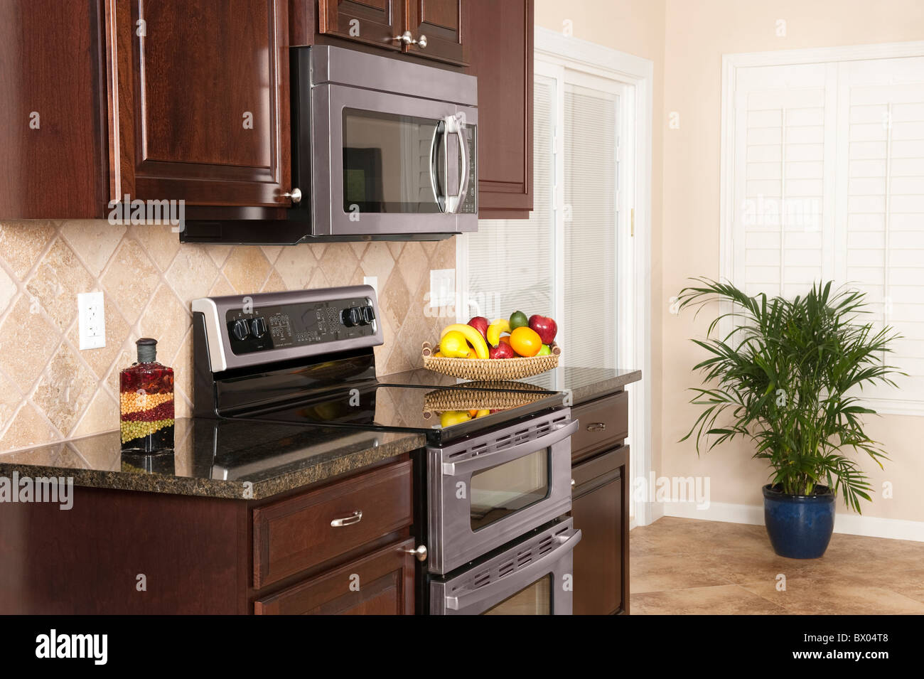 Eine kleine moderne Küche mit Küchengeräten aus Edelstahl, modernes Mobiliar und schöne Fensterläden umgebaut zu einem Earthtone-Thema. Stockfoto