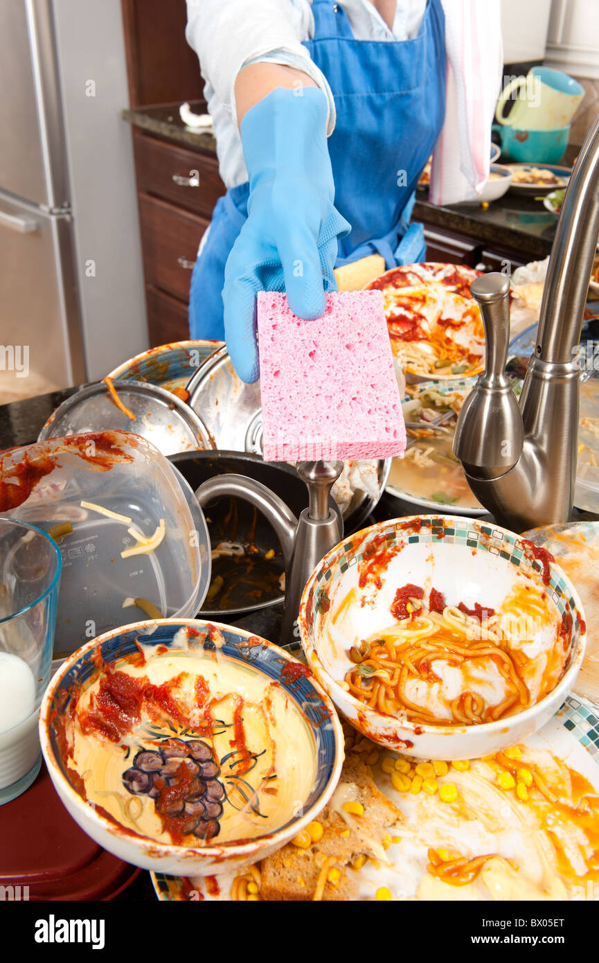 Eine Hausfrau bietet ihr Gericht Schwamm zu helfen, Geschirr spülen Stockfoto