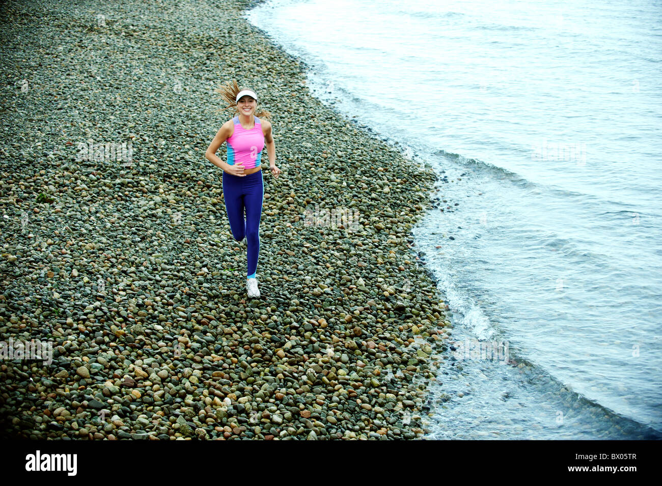 Kaukasische Frau läuft am Kiesstrand Stockfoto