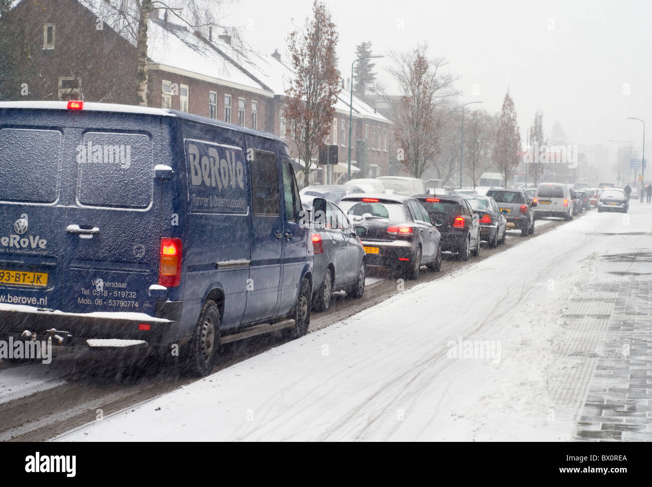 Verkehr, der langsam seinen Weg auf einer verschneiten Straße in den Niederlanden Stockfoto