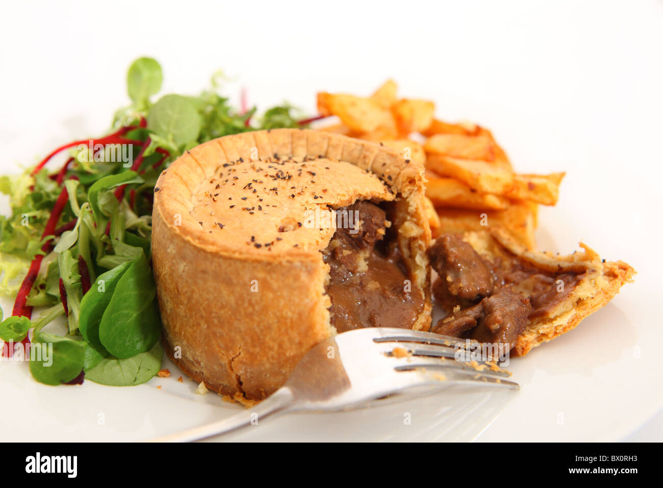 Ein erhöhter Steak Pie, mit französischen gebratenen Kartoffel-Chips und einem grünen Salat serviert. Stockfoto