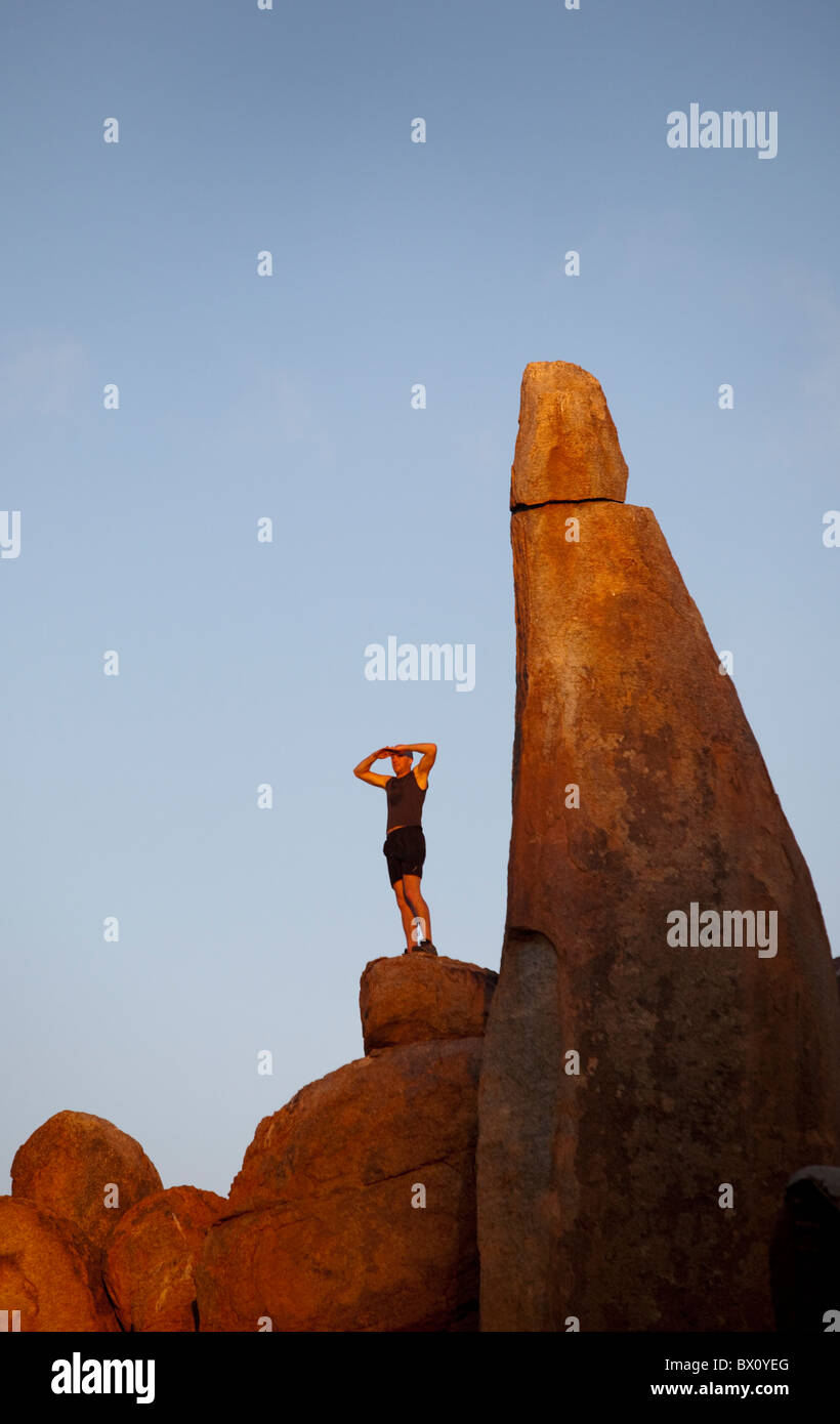 Mann steht auf hohen Felsen bei Sonnenuntergang. Stockfoto