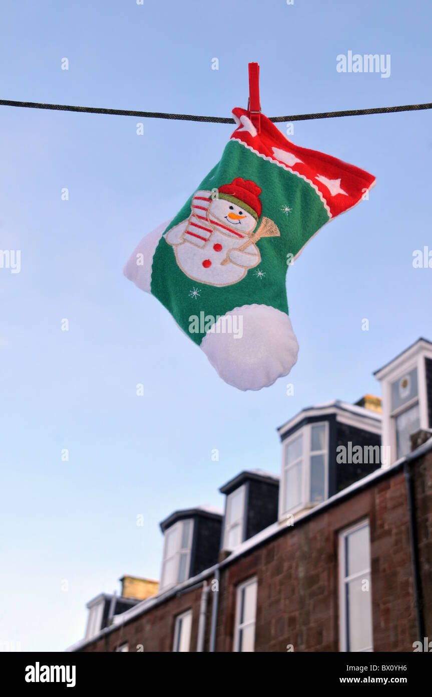Ein Weihnachts-Strumpf hängen eine Wäscheleine mit einer Reihe von Wohnungen im Hintergrund. Stockfoto