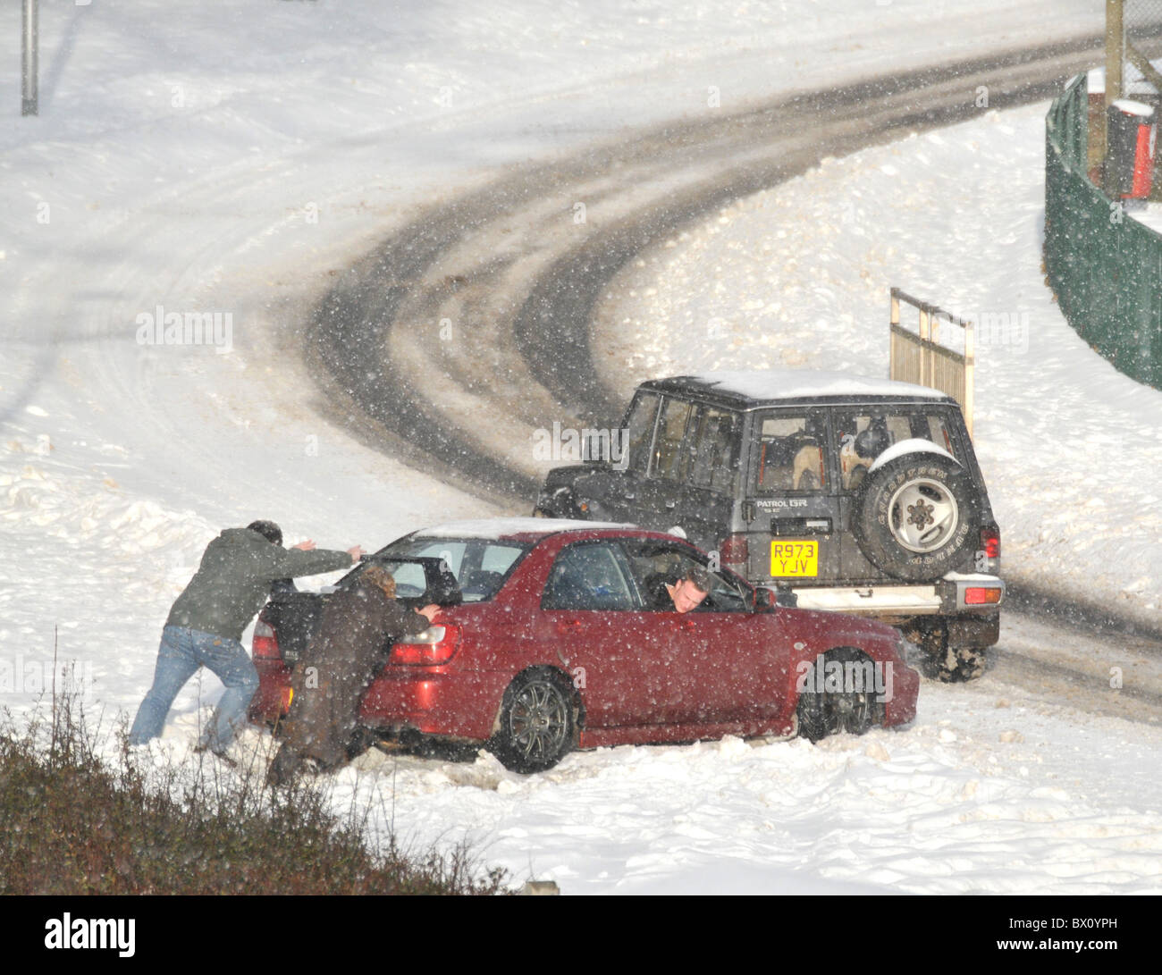 Ein paar versuchen eine eingeschlossene Auto aus einer Schneewehe. Stockfoto