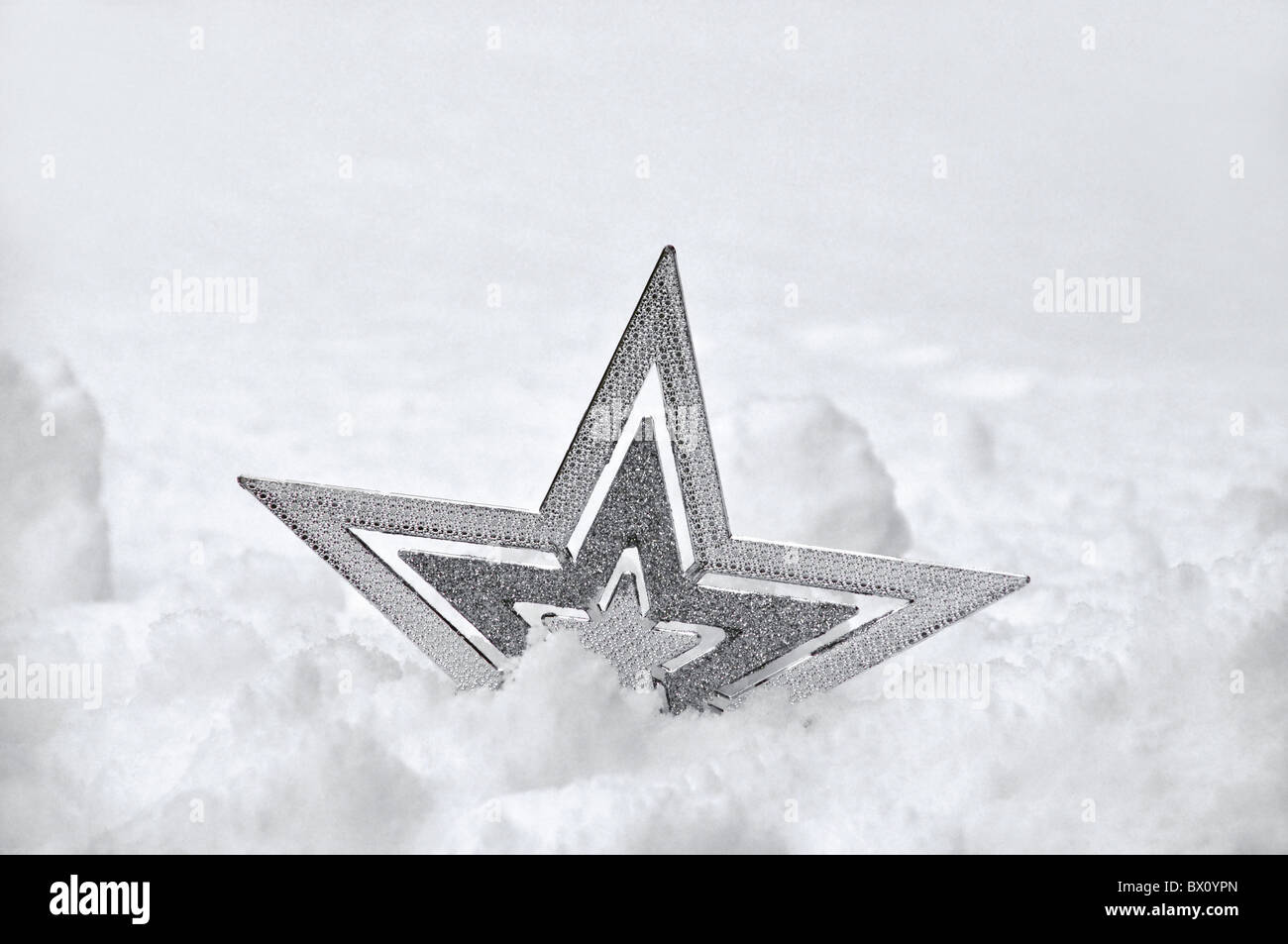Eine silberne Weihnachtsdekoration Sterne halb versunken im Schnee. Stockfoto