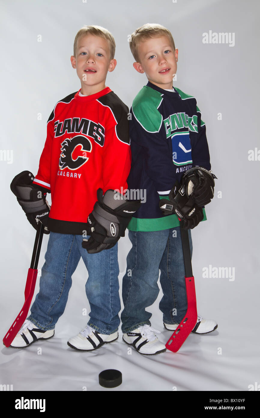 6 Jahre alten eineiigen Zwillinge tragen Eishockey Trikots Stockfoto