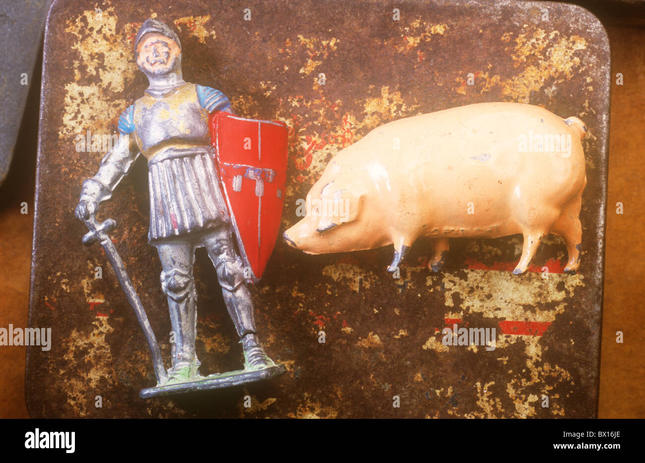 Nahaufnahme von zerkratzten Metall Blei Modelle der Ritter in Rüstung mit Schwert und Schild und große rosa Schwein auf rostigen Zinn Stockfoto