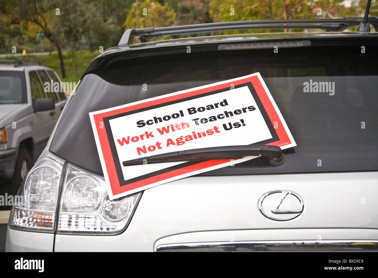 Fahrzeuge in Schule Parkplatz Anzeige Plakat zeigt Lehrer Unzufriedenheit mit der Politik der Schulbehörde. © Myrleen Pearson Stockfoto