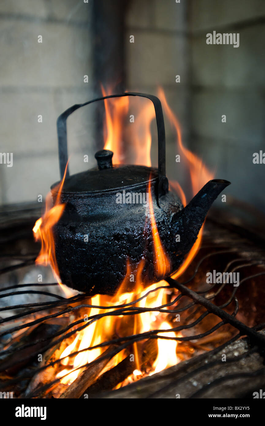 Eine rußgeschwärzten Teekanne sitzt am offenen Feuer. Stockfoto