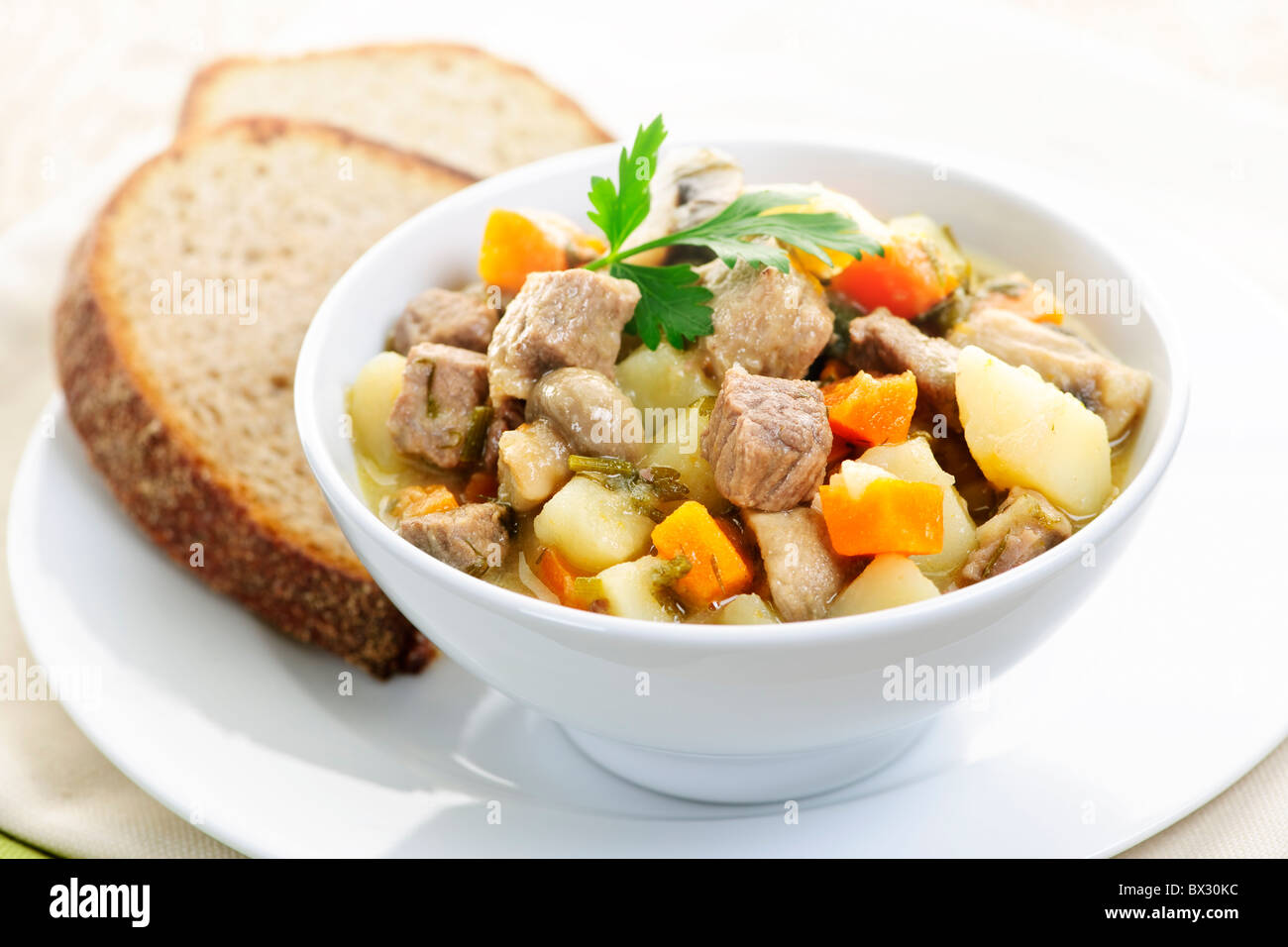 Schüssel mit herzhaften Rindfleisch-Eintopf mit Gemüse serviert mit Roggenbrot Stockfoto