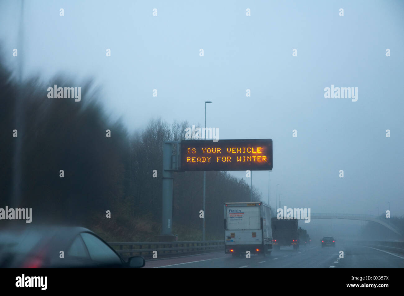 "Ist Ihr Fahrzeug bereit für den Winter" - Autobahn Zeichen aus Sicht der Fahrer an einem nebeligen winterlichen Tag gesehen. Stockfoto