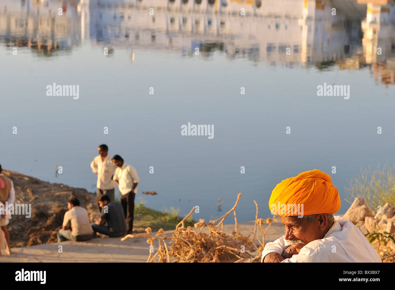 Ein Rajput mit einem hellen orange Turban anstarren In Arbeit am Heiligen See Pushkar. Stockfoto