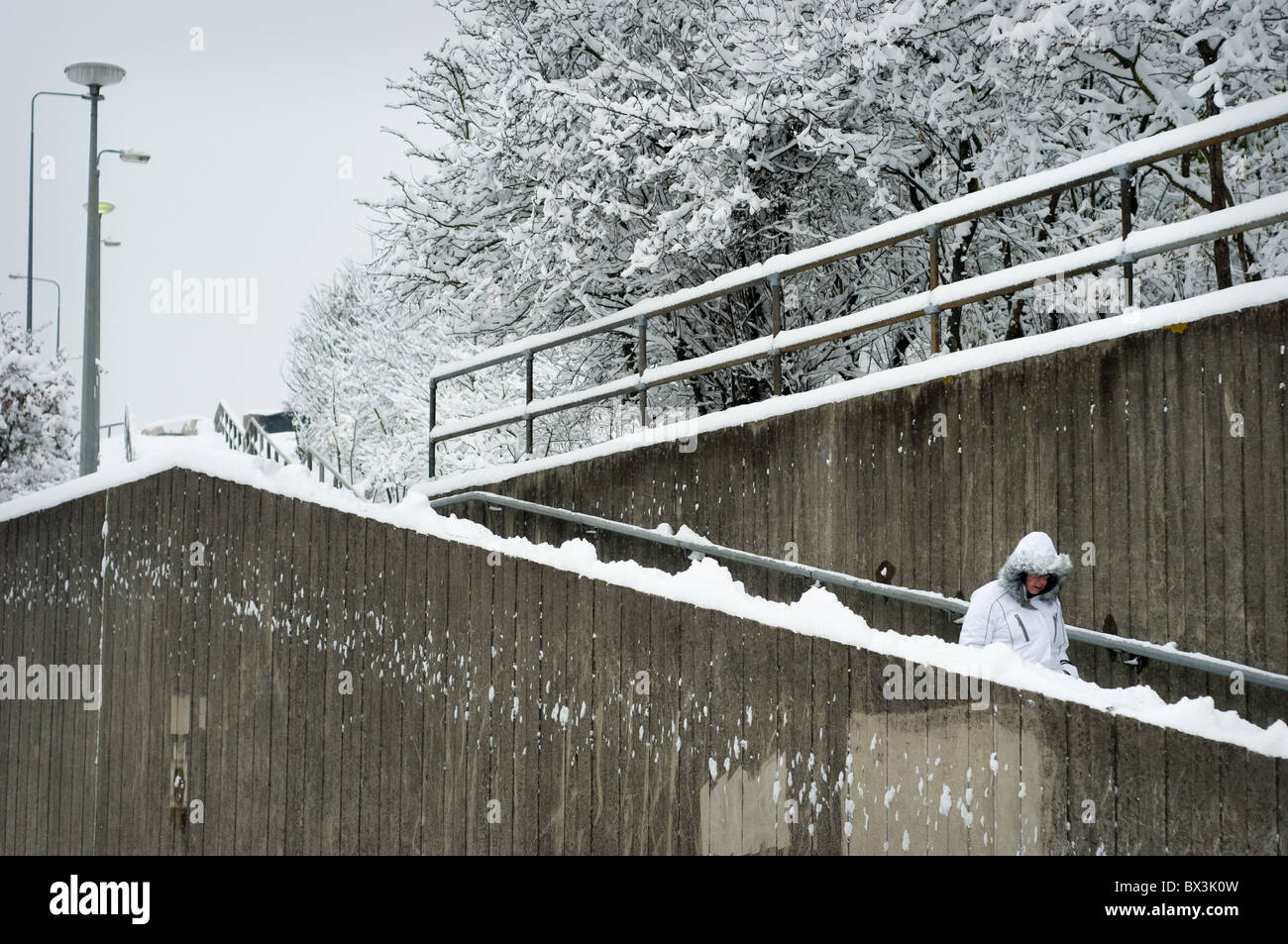 Eine Frau zu Fuß einige Stufen hinunter nach einer frühen Winterschnee fallen. Stockfoto