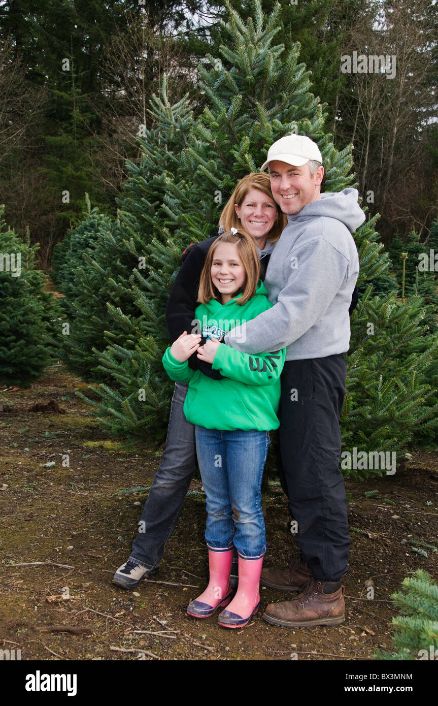 Eine glückliche Familie posiert vor einer Tanne im Freien im Winter. Stockfoto