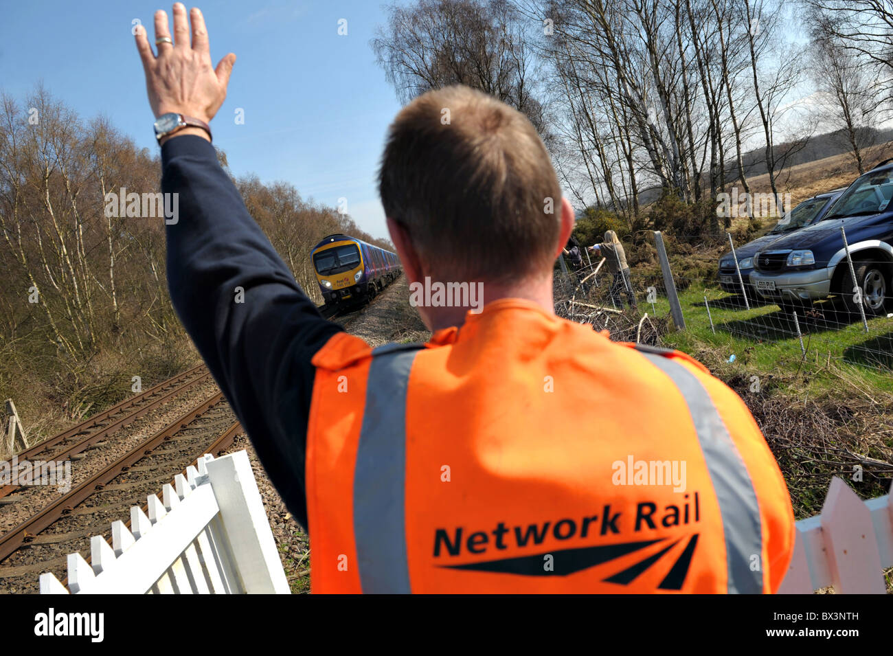 Ein Network Rail Crossing Keeper winkt der Fahrer des ersten nördlichen Zug in der Nähe von Scarborough Stockfoto