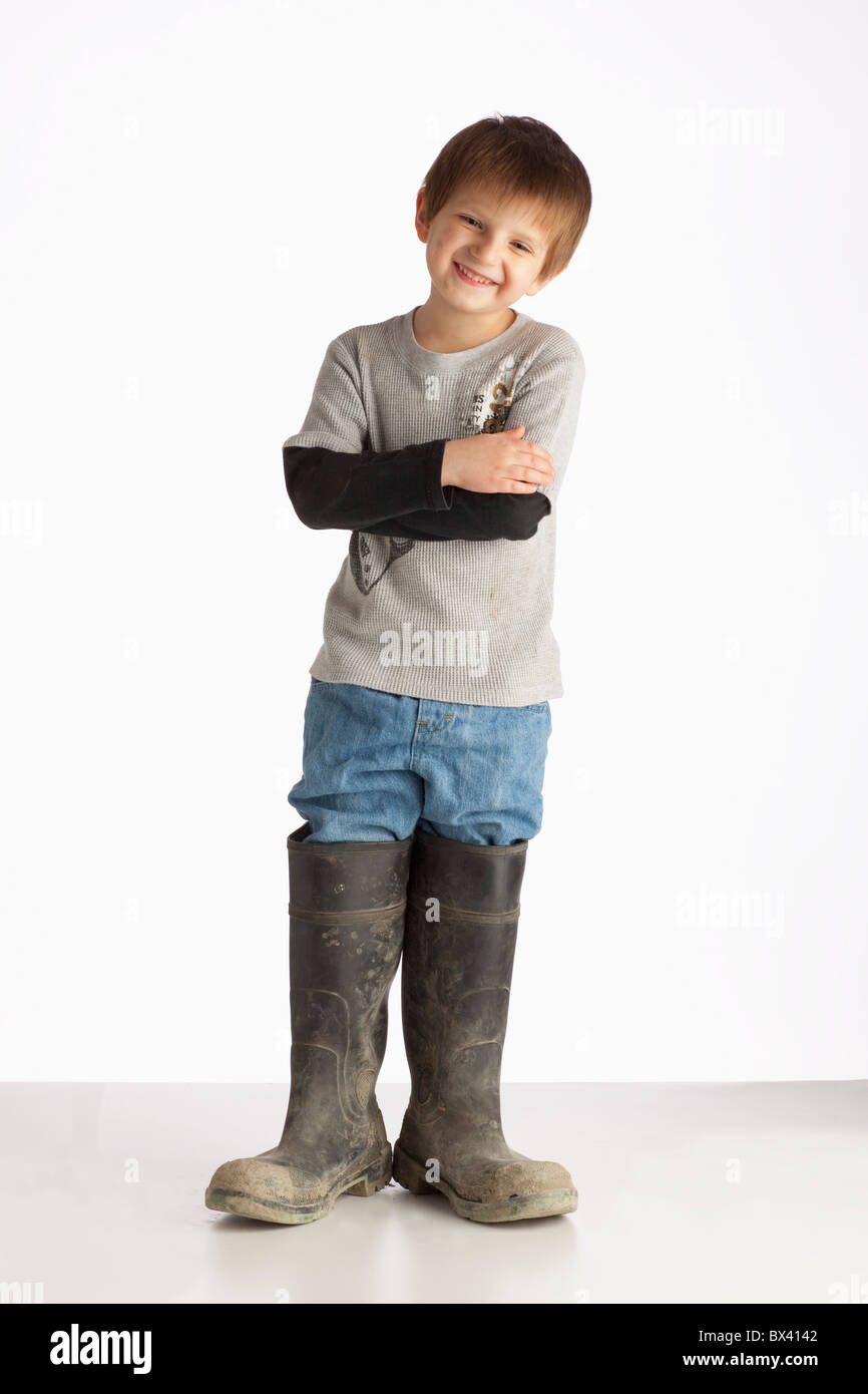 Ein Junge trägt übergroße Gummistiefel Stockfoto