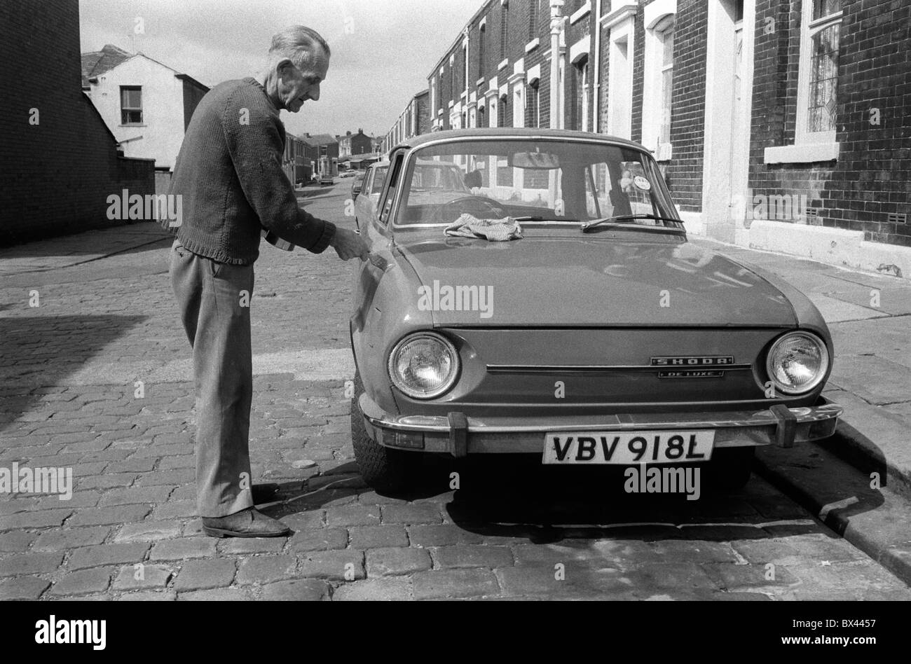 Arbeiter-Klasse-weißes Männergemälde über Rostschäden an seinem Honda-Auto Blackburn Lancashire 1983. Straßenszene Kopfsteinpflasterstraßen Terrassenhaus Straßenszene Daily Life 1980s UK. HOMER SYKES Stockfoto