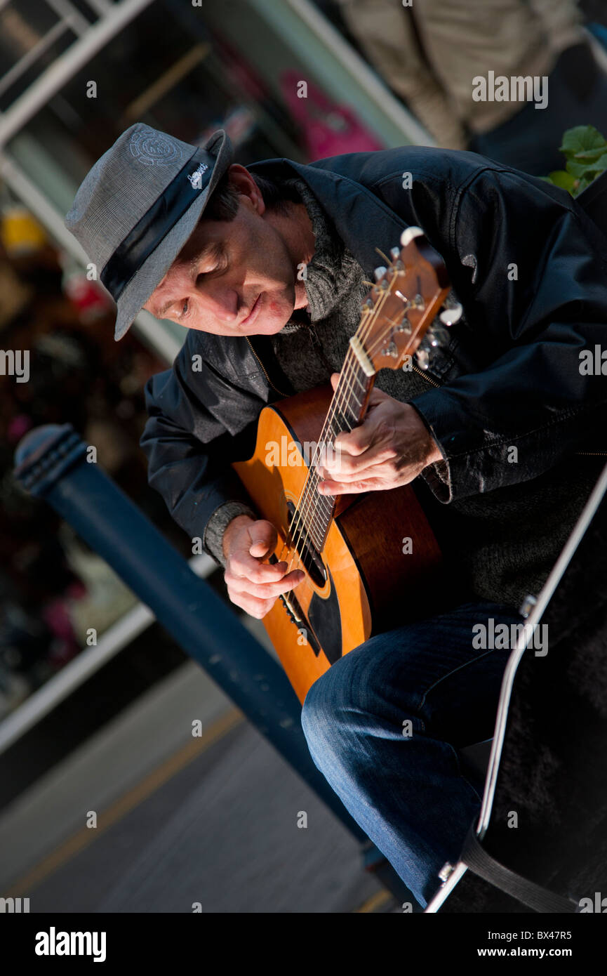 Ein Mann Straßenmusik Gitarre spielen auf der Straße, Aberystwyth Wales UK Stockfoto