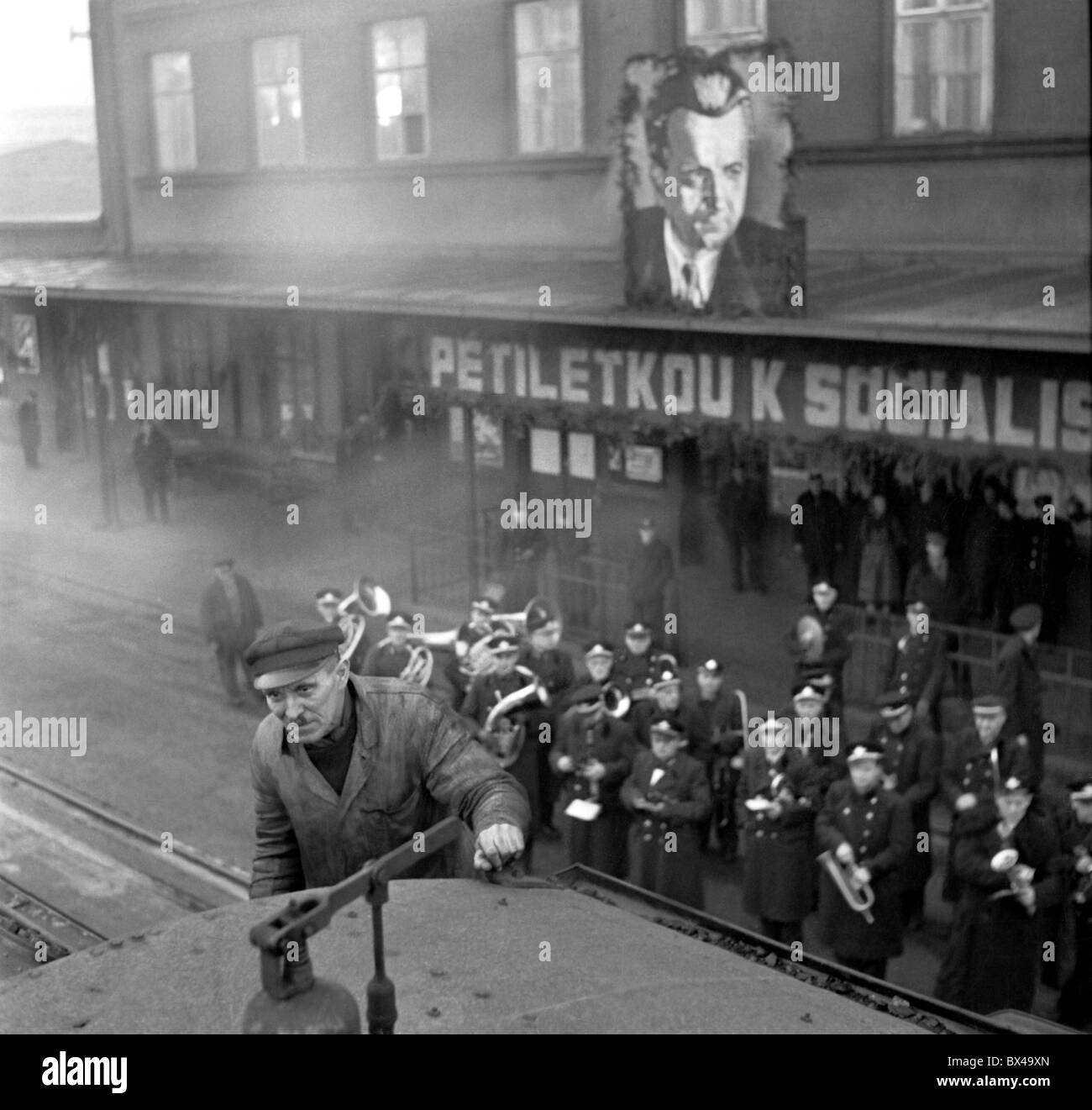 Tschechoslowakei - Prag 1949. Band spielt Volksmusik und riesige Klement Gottwlad Porträt hängt vom Gebäude während der Stockfoto