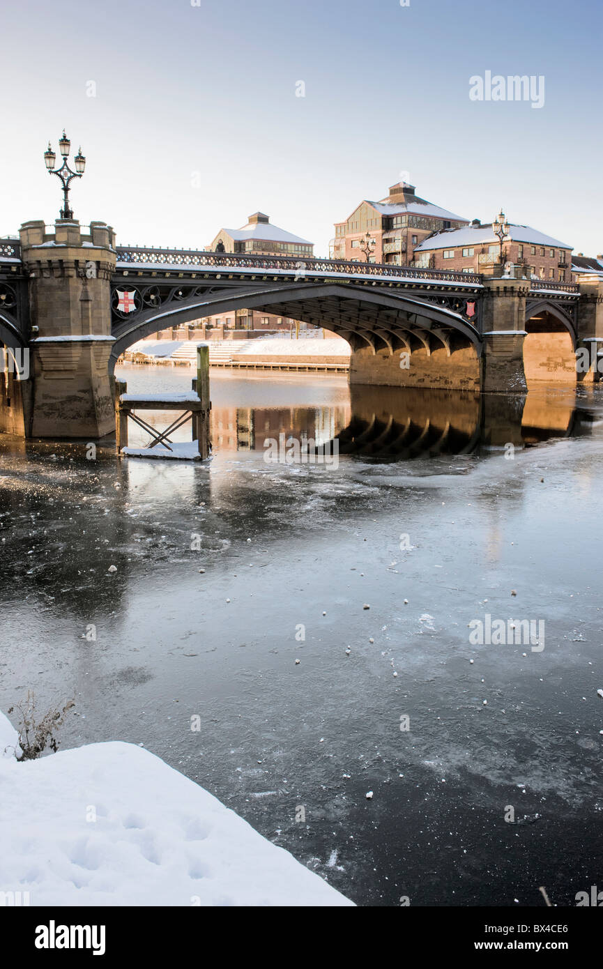 Die Skeldergate Bridge wurde von der South Esplanade in York aus aufgenommen und überquerte den gefrorenen Fluss Ouse mit dem Aviva Office-Gebäude in der Ferne. Stockfoto