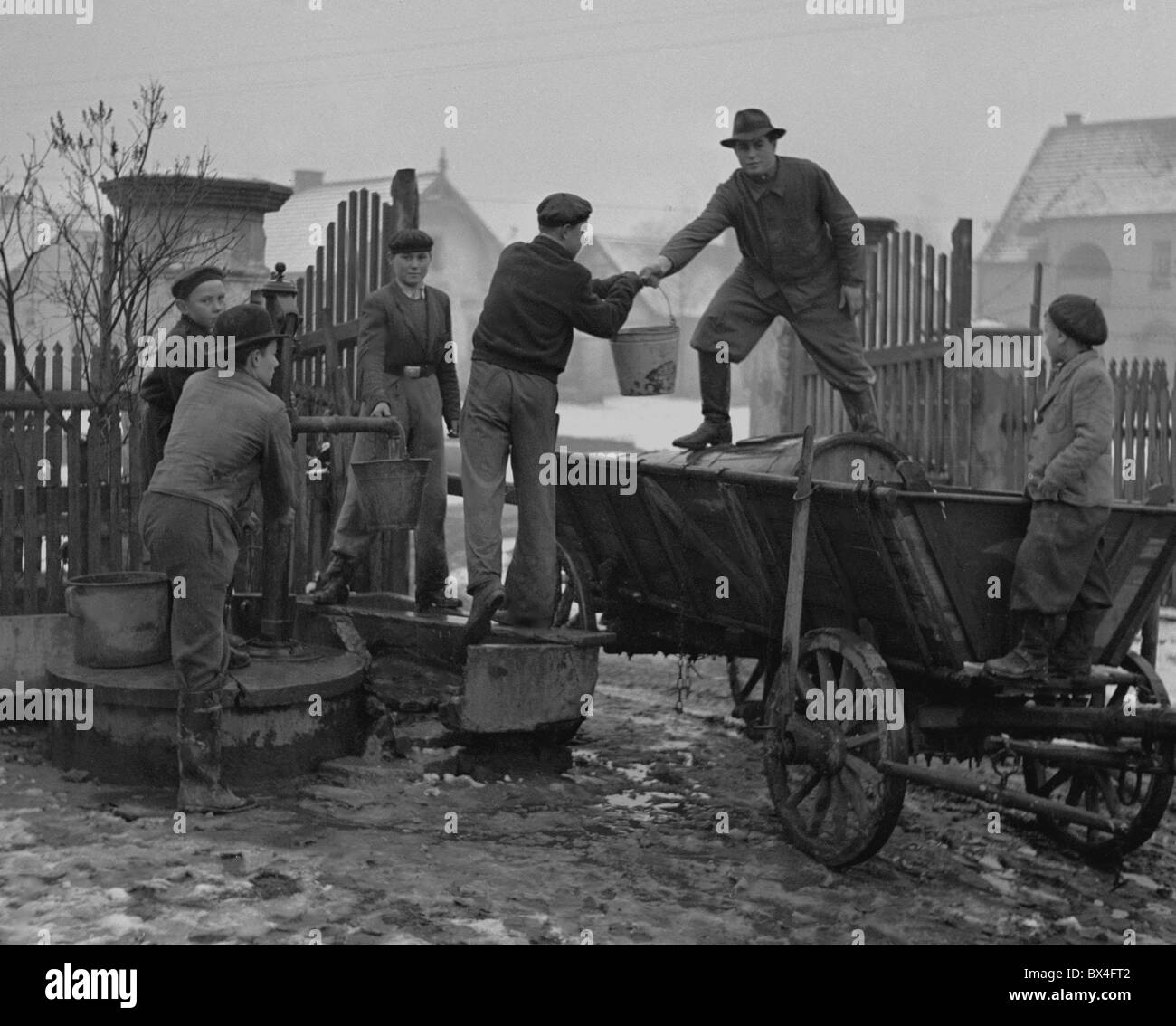 Tschechoslowakei - Horatev, 1950. Männer Pumpe Wasser aus gut und füllen Sie den Lauf auf Anhänger. CTK Vintage Photo Stockfoto
