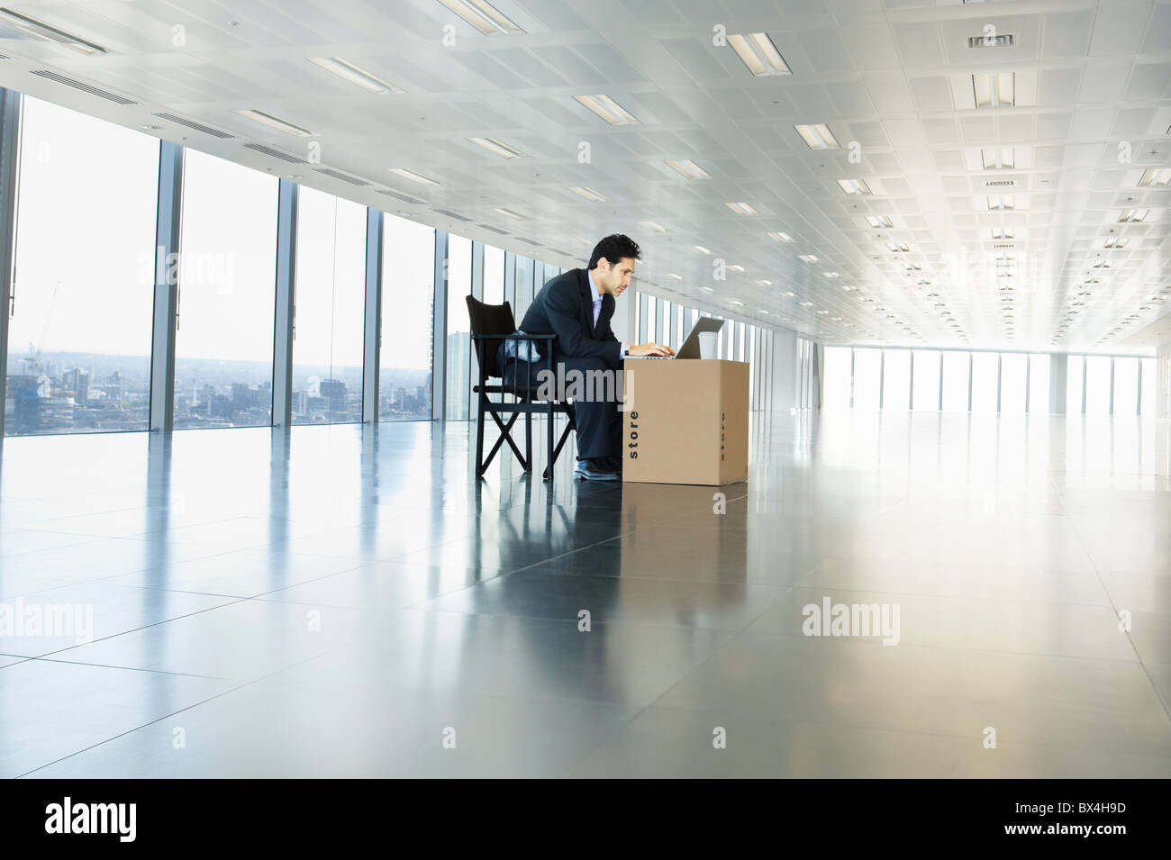 Geschäftsmann, arbeiten am Laptop in leeren Büroflächen mit Karton als Schreibtisch Stockfoto