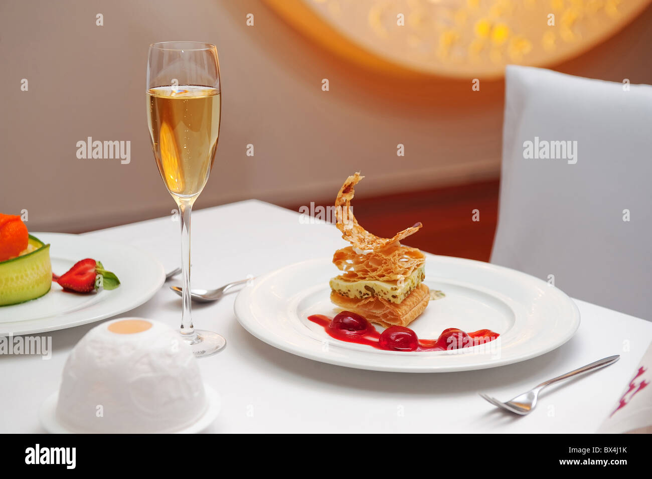 Ein leckeres Dessert mit Beerensauce und Glas Wein schön präsentiert. Stockfoto