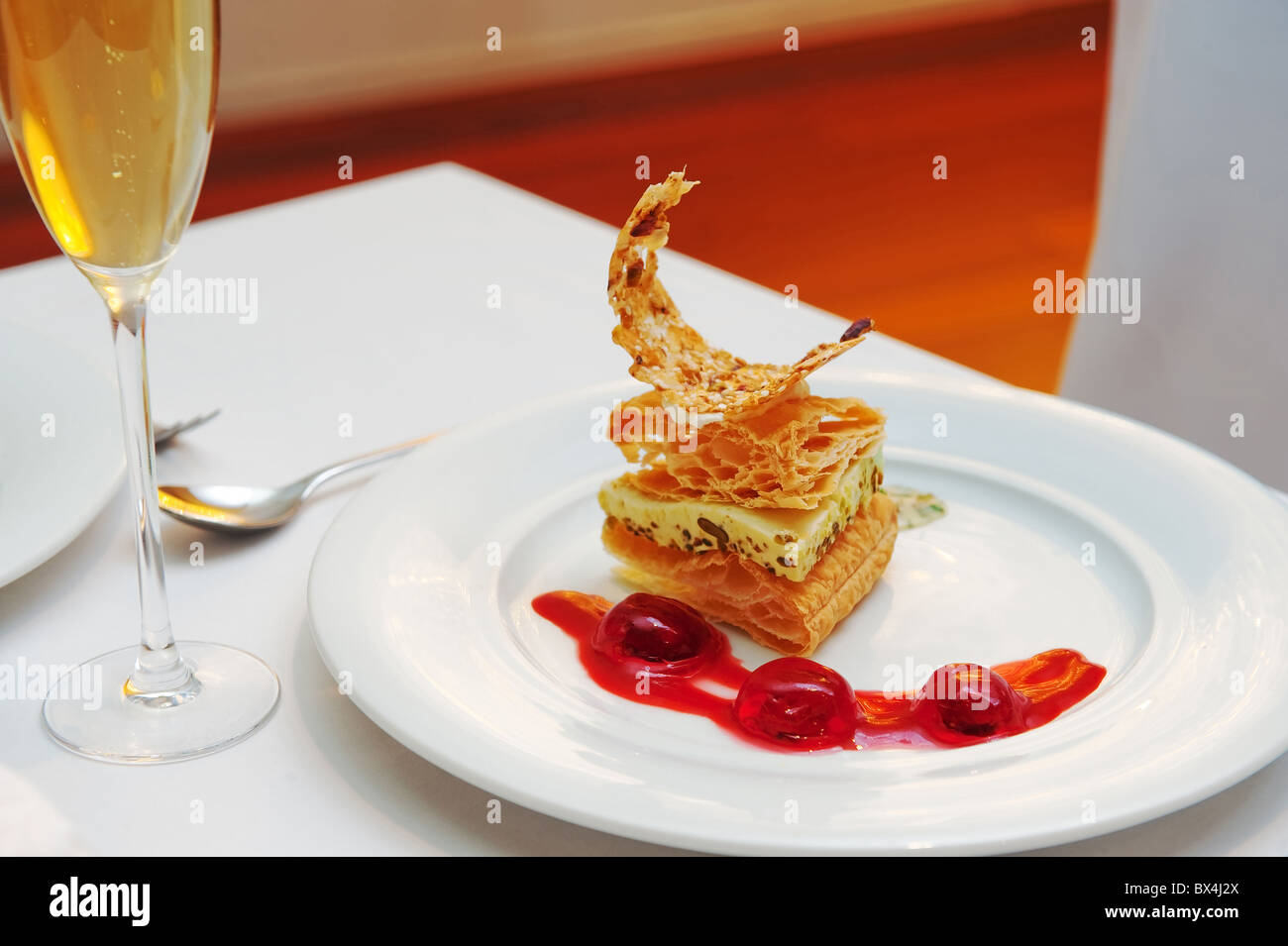 Ein leckeres Dessert mit Beerensauce und Glas Wein schön präsentiert. Stockfoto