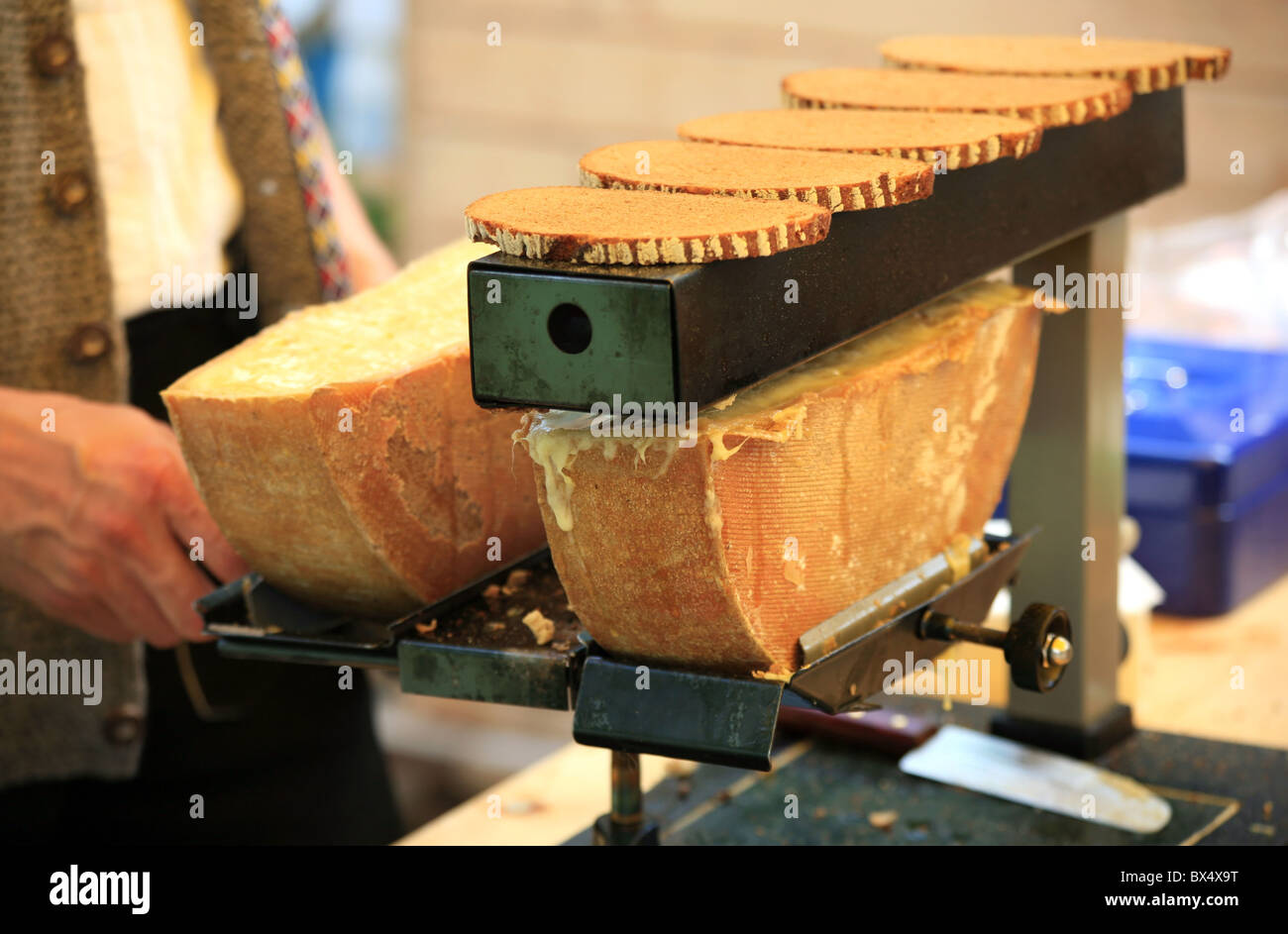 Mann Schweizer Raclette-Käse schmelzen, um es auf geröstetem Schwarzbrot Stockfoto