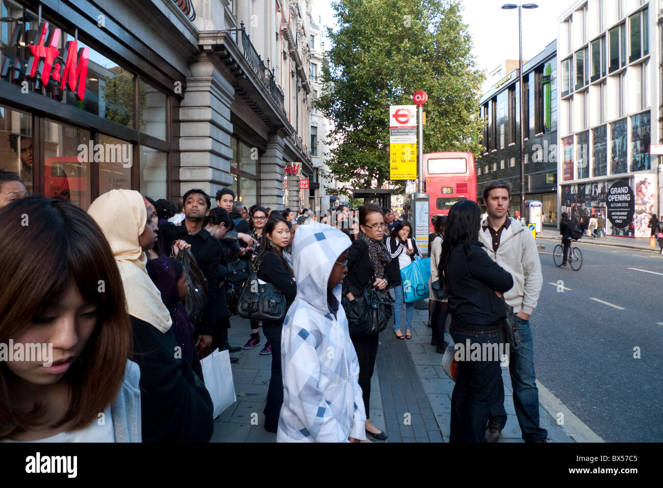 Multikulturelle Menschenmenge stehend Warten auf einen Bus in der Oxford Street Bushaltestelle vor H&M Store in der Nähe von Oxford Circus London England UK KATHY DEWITT Stockfoto