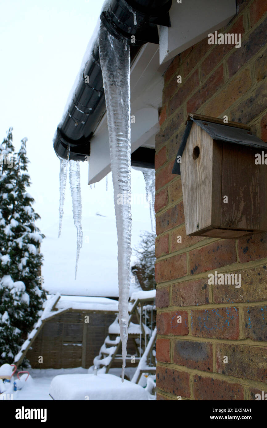 Eiszapfen hängen von Haus Dachrinnen Stockfoto