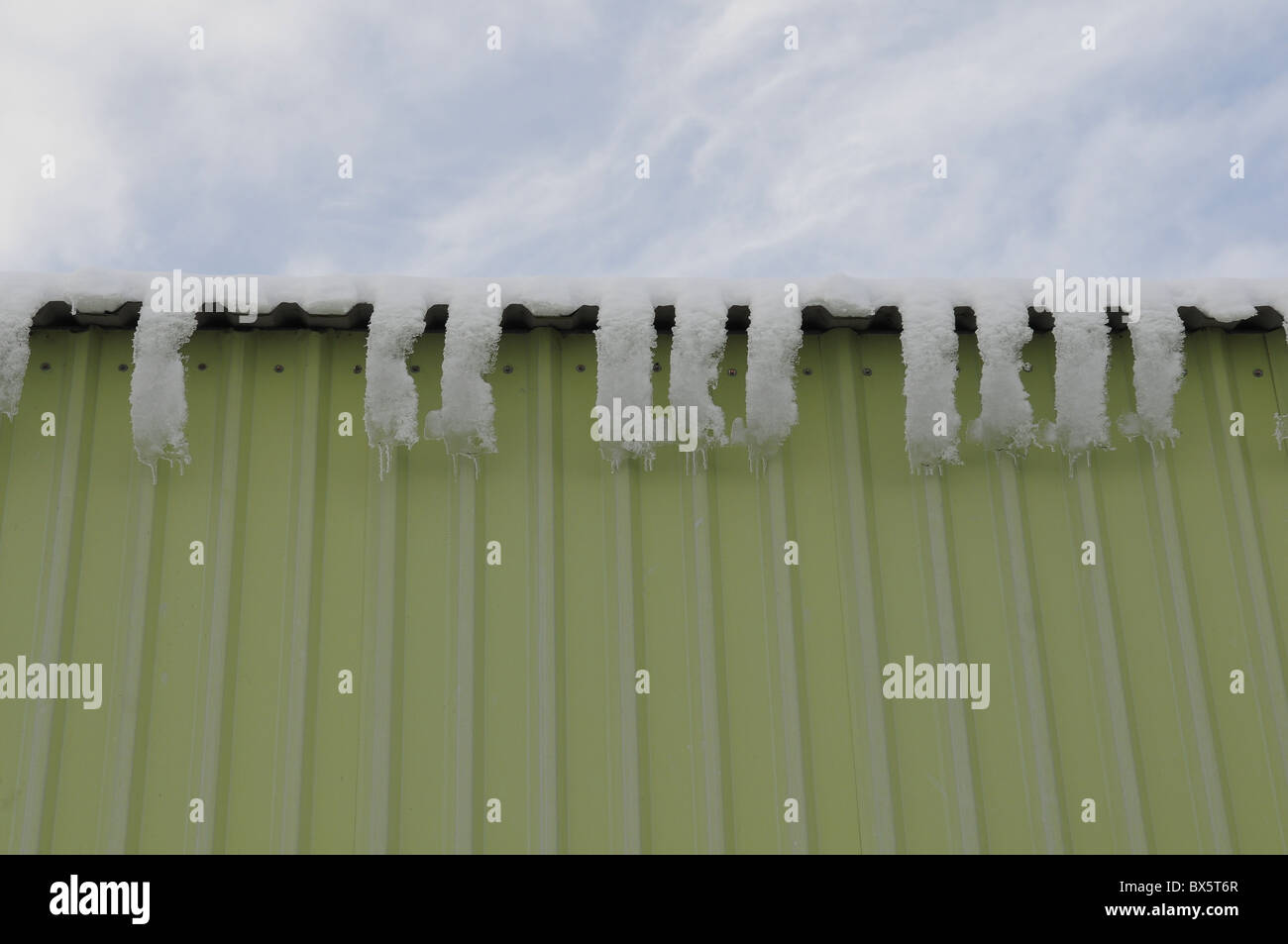 Eiszapfen, die entsteht, wenn Schnee auf dem Dach eines landwirtschaftlichen Gebäudes geschmolzen Stockfoto