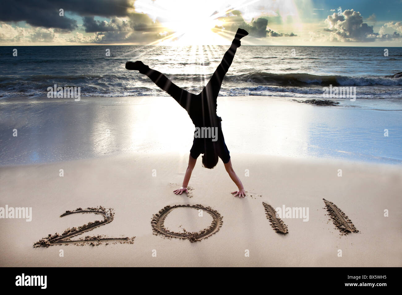 Frohes neues Jahr 2011 am Strand von Sunrise. junger Mann Handstand und feiern. Stockfoto