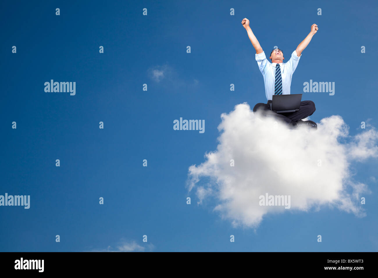 junger Geschäftsmann mit Computer auf der Wolke sitzen Stockfoto