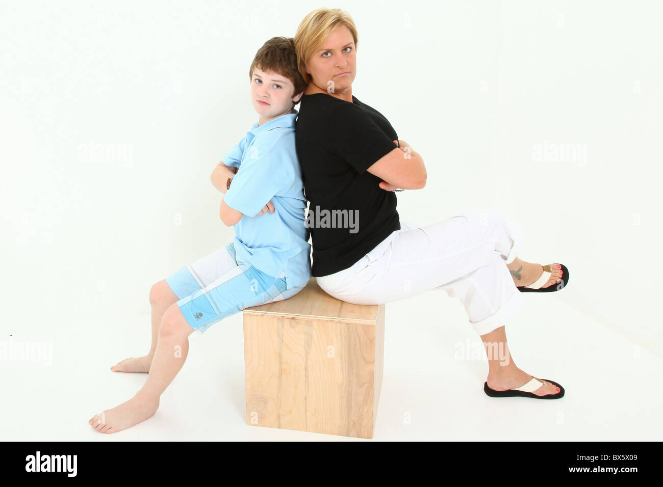 Mutter und Sohn sitzen auf Holzblock über weißen wütend in Richtung Kamera suchen. Stockfoto