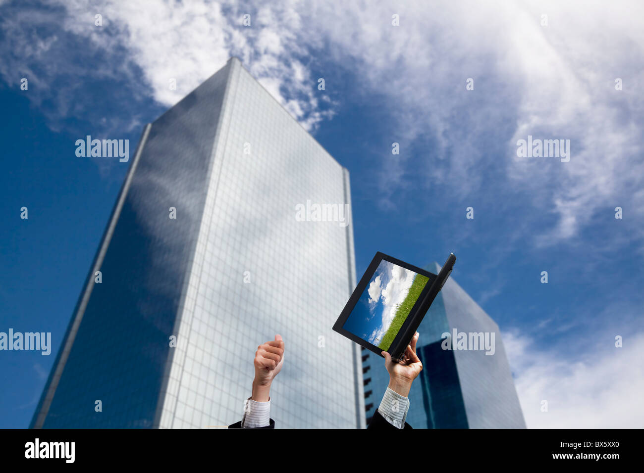 Geschäftsmann Hand erhaben Computer und Daumen vor modernen Gebäude Stockfoto