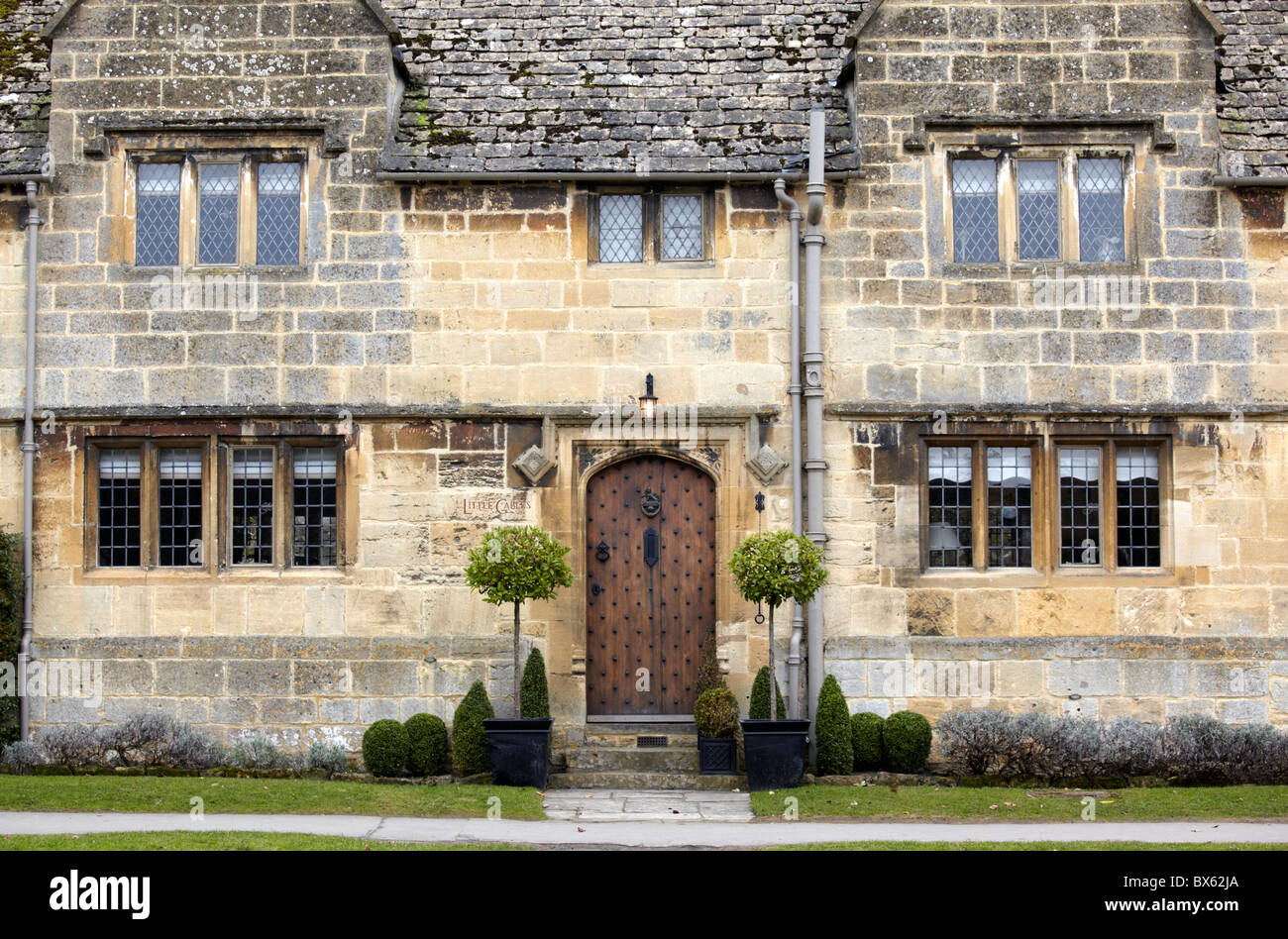 Abgeschnittene Box und Lorbeerbäumen vor einem Cotswold-Stein-Haus in Broadway, Worcestershire Stockfoto