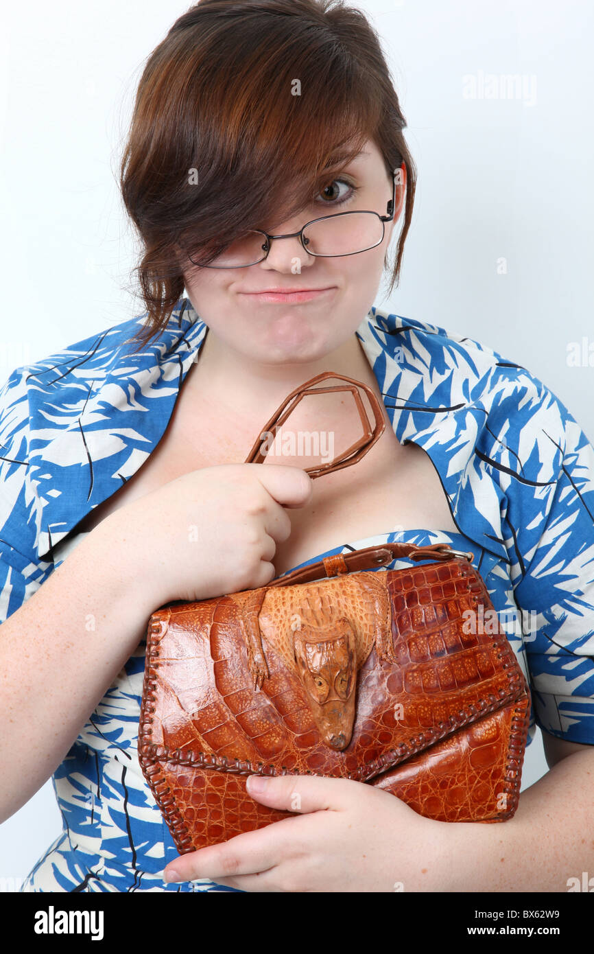 Fräulein Dresed in Retro-Kleidung mit Alligator Geldbörse, Brille, machen dumme Lächeln. Stockfoto