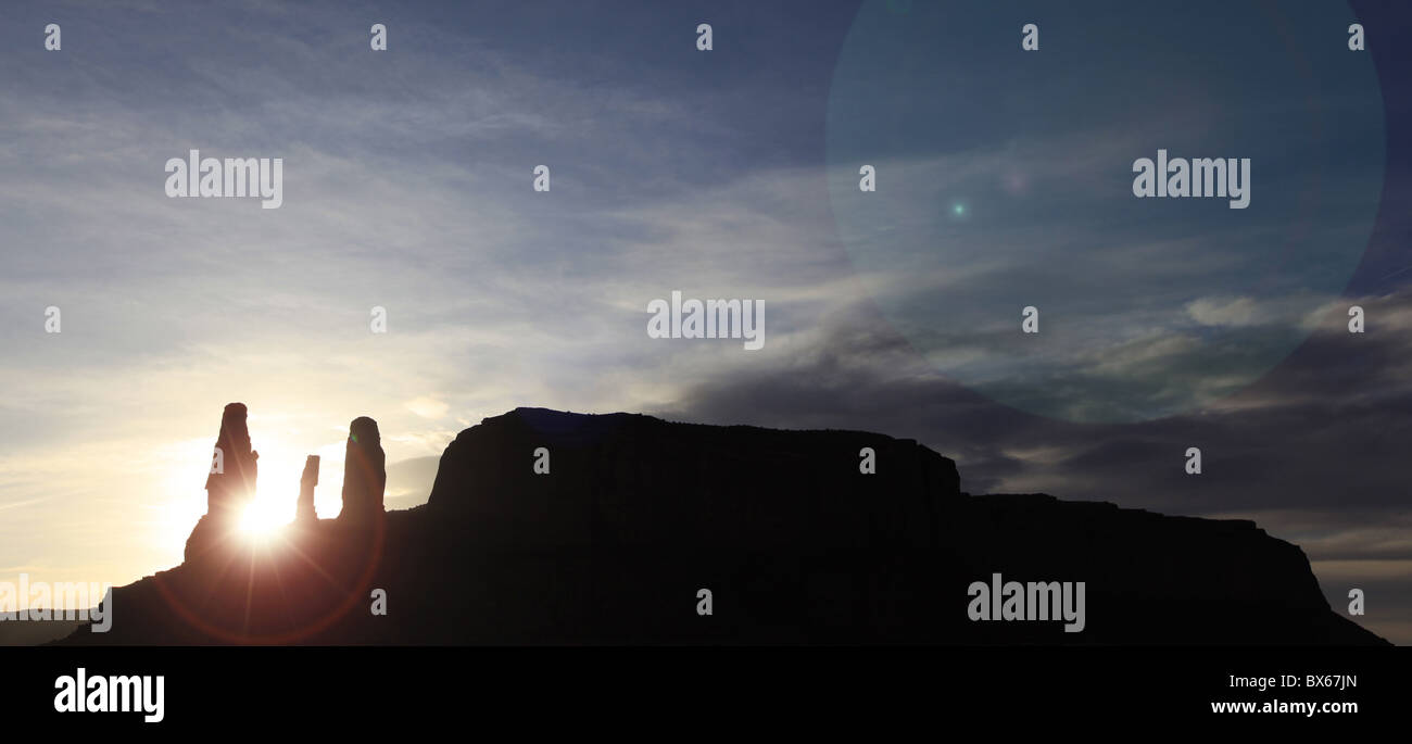 Die Abendsonne versinkt zwischen Triple-Monolith in den Sandsteinfelsen und Zinnen an Monument Valley, Arizona, USA Stockfoto
