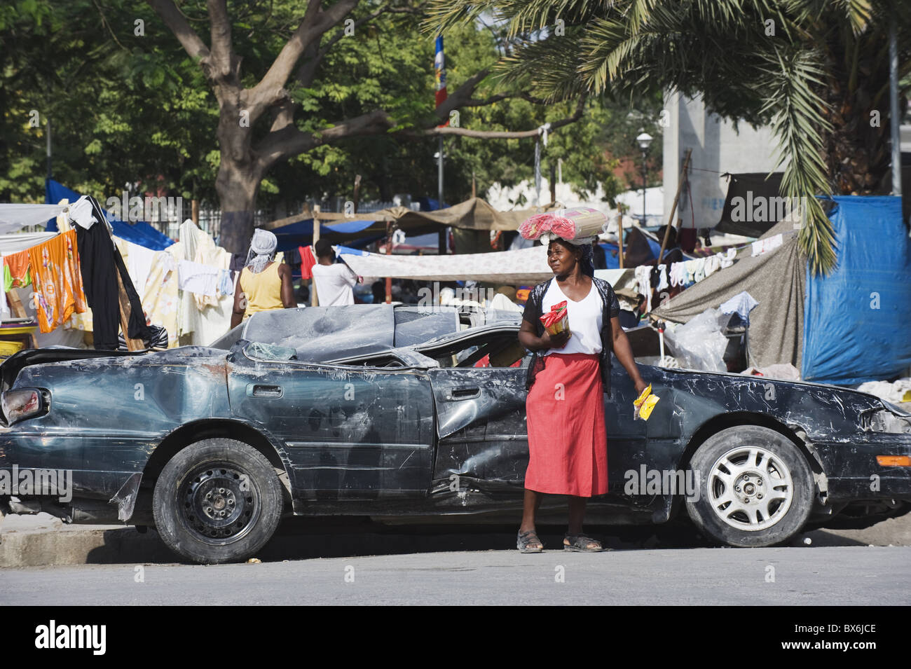 Frau vor ein beschädigtes Auto, Januar 2010 Erdbeben, Innenstadt, Port au Prince, Haiti, West Indies Stockfoto