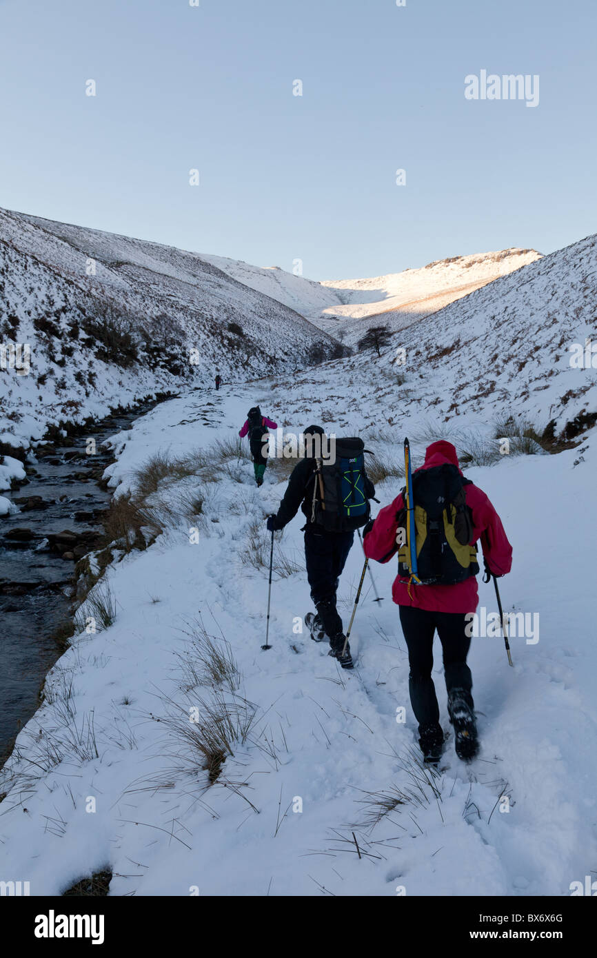 Männliche Spaziergänger durch Fairbrook im Winter auf Kinder Scout im Dunkeln Peak Teil der Peak District National Park, Derbyshire, UK Stockfoto