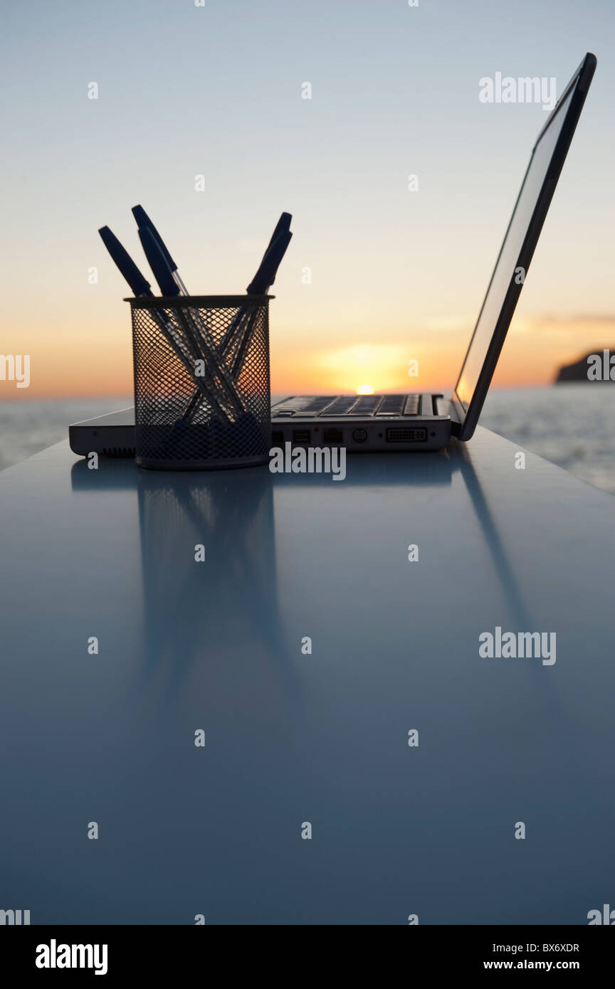 Ein Laptop mit einem Sonnenuntergang hinter Stockfoto