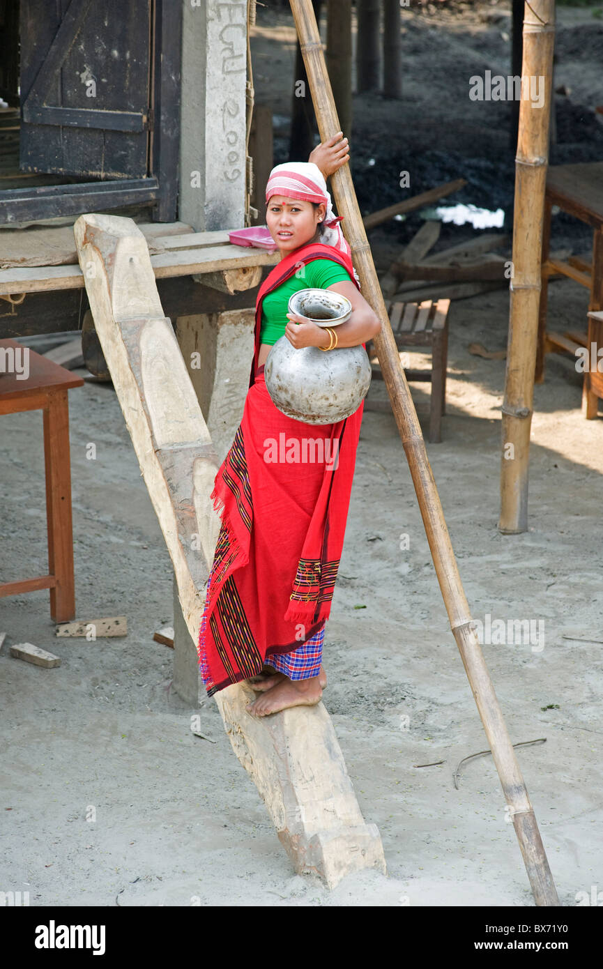 Assamesisch Stammes-Dorf Frau mit Wasserkrug, einfachen hölzernen Treppenstufen bis zu ihrem Haus, Majuli Insel, Assam, Indien Stockfoto