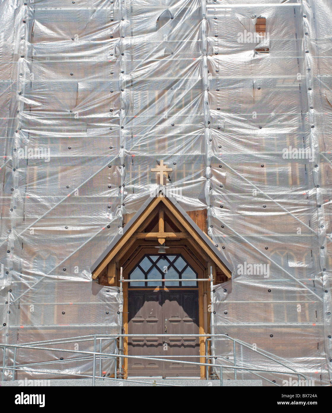 Haupttür und Plastikplanen bedecken die Fassade einer hölzernen Lutherischen Kirche in Lapinlahti während der Renovierungsarbeiten in Finnland Stockfoto