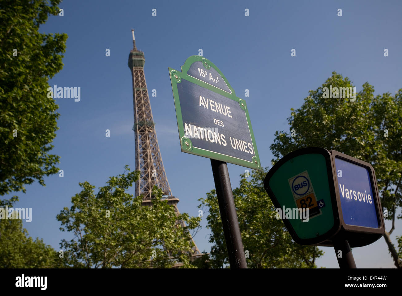 Zeichen für Avenue des Nations Unies und Varsovie Bushaltestelle mit dem Eiffelturm hinter den Bäumen Stockfoto