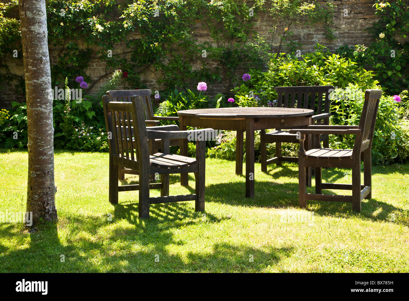 Gartenmöbel aus Holz in einer entspannenden Ecke von einem ummauerten englischen Country-Sommergarten Stockfoto