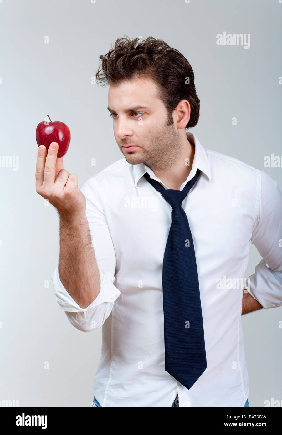 Mann in weißem Hemd und Krawatte halten Sie suchen roter Apfel - isoliert auf grau Stockfoto