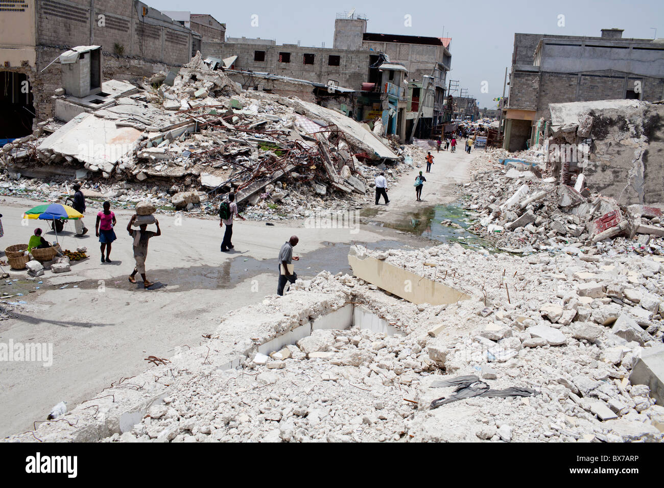 Fußgänger schlendern Sie vorbei an riesigen Haufen von Erdbeben Schutt am 8. Juli 2010 in Port-au-Prince, Haiti. Stockfoto