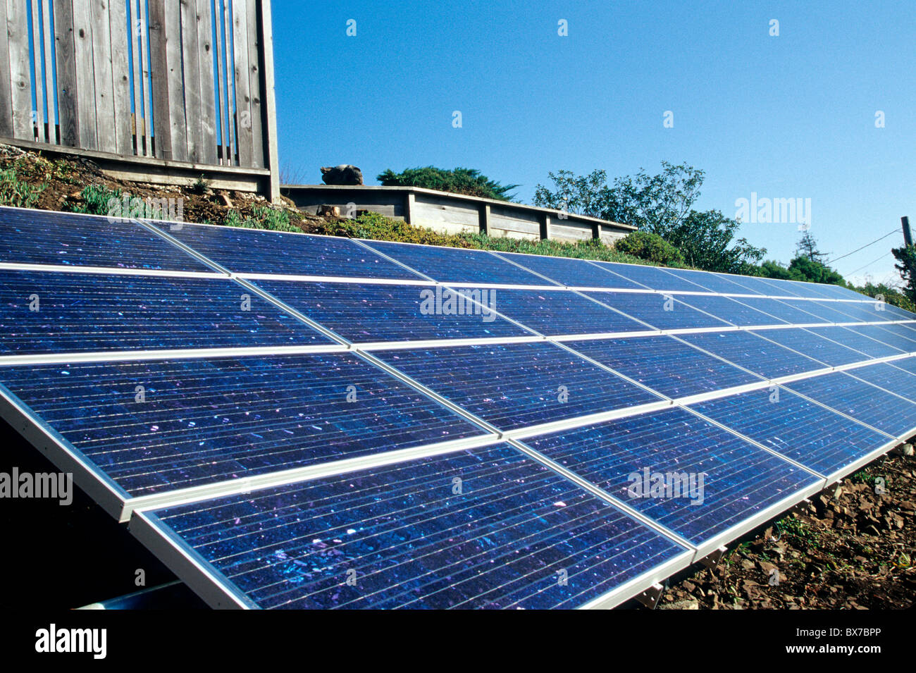 Elektrische Sonnenkollektoren installiert am Hang unterhalb der Familie zu Hause, Stockfoto